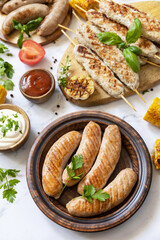 Summer party food. Grill food menu. Various bbq grilled sausages with fresh herbs and spices on marble tabletop.