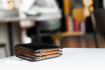 Soft tone of Money and credit card in a leather wallet on wooden table and bill slip background