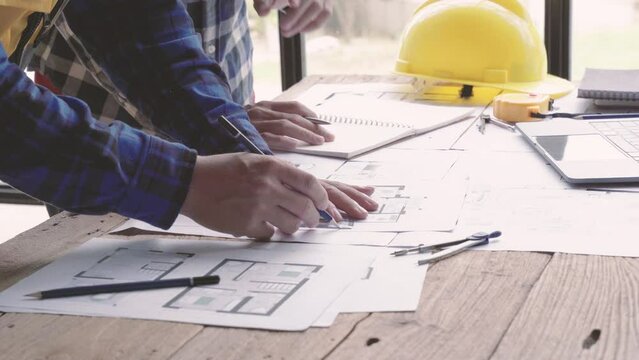 two Architects Discussing Plan Together At Desk With Blueprints. Close up of hands of an architects. designers architects team project working on desk close up. 4 k. hand pointing, blueprint decorator