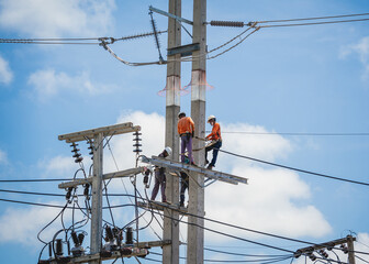 Electricians is repairing high voltage wires on electric power pole