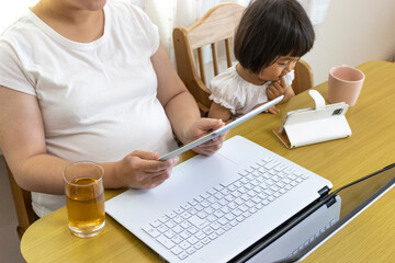 在宅勤務の母親(30代、日本人)と、スマホを見る赤ちゃん（1歳11ヶ月、日本人、女の子）