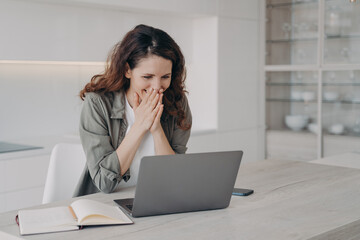 Excited young businesswoman has video call on laptop. Corporate internet session.