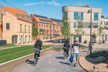 Beautiful girl riding a bike on a new bike path or road between modern buildings in the center of Odense, Denmark with cyclists and pedestrians 