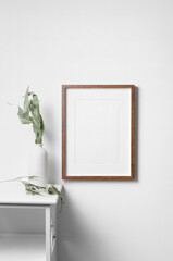 Vertical frame mockup on white wall with botanical decorations, blank mockup for artwork