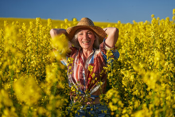 Naklejka na ściany i meble Senior woman in a canola field