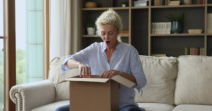 Older woman opens received parcel feels satisfied. Ecommerce buyer, ordered goods for home retail services store ad, package from relatives. Surprise and gift, express delivery services client concept