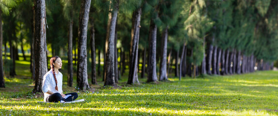 Woman relaxingly practicing meditation in the pine forest to attain happiness from inner peace...