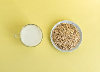 Flat lay oatmeal, oatmeal cookies on a white plate on a yellow background, top view, the concept of healthy eating and making cereal or cookies. High-quality photo