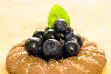 Cookies with blueberries and a leaf on a wooden background