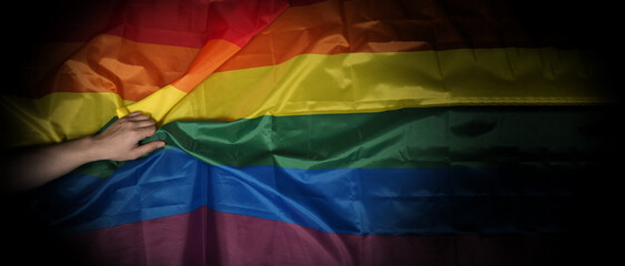 LGBTQ pride flag on black background. Lgbt rainbow flag in gay hand. Represent symbol of freedom...