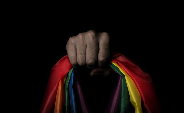 LGBTQ pride flag on black background. Lgbt rainbow flag in gay hand. Represent symbol of freedom peace equality and love and respect  diversity of sexuality. Lesbian Gay Bi sexsual Transgender Queer.