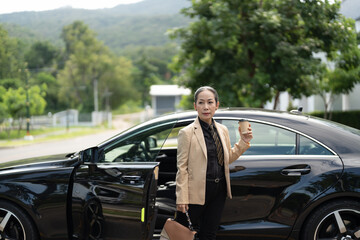 Asian mature woman disembarking the luxury car