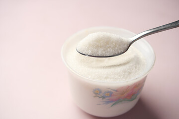 white sugar and spoon in a container on black background,
