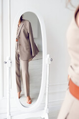 Reflection in the mirror of a woman in a three-piece suit. Business style for women.
