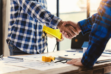 Architect and engineer construction workers shaking hands while working for teamwork and cooperation concept after finish an agreement in the office construction site, success collaboration concept
