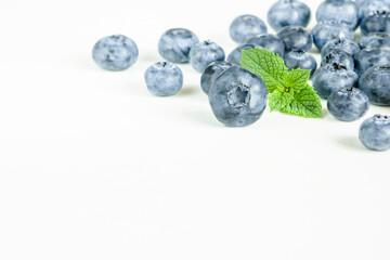 Blueberries with green mint leaf on white background closeup. Copy space