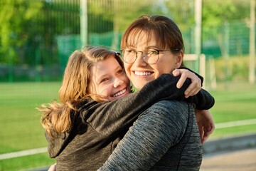 Fototapeta na wymiar Portrait of happy mom and preteen daughter hugging together outdoor