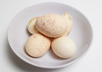Fototapeta na wymiar A bowl of fresh Turkey Eggs on a white background Large speckled eggs shells