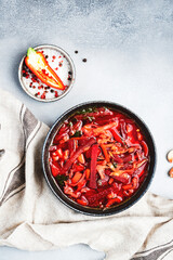 Summer Vegetable Soup with  cabbage, beets, and herbs. Russian borscht in plate on grey kitchen table background, top view, copy space. Vegan, vegetarian local food