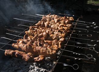 
Large pieces of pork meat are fried on coals in the grill. Smoke from coal, dark...