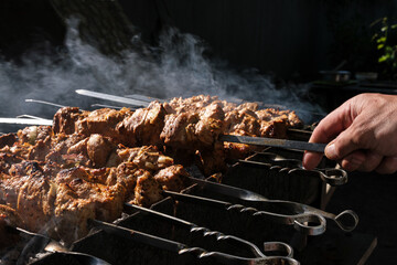 a man roasts meat on a fire. Close-up of hands and shish kebab. Cooking pork neck on the grill....