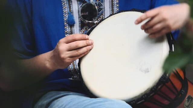 Man's Hand with Musical Instrument African Djembe Meinl. A man is dressed in Ukrainian vyshyvanka