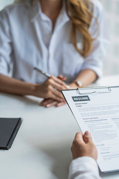 Business, career and recruitment concept - young asian woman smiling and holding resume, while interviewing as candidate for job in big company