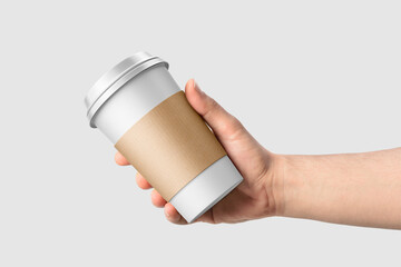 Paper coffee cup with sleeve in a hand mockup template, isolated on light grey background. High...