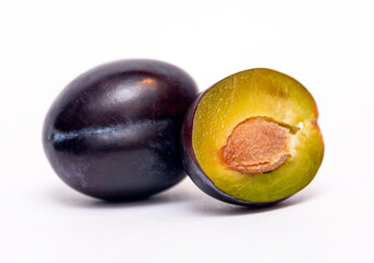 whole plum and half a plum on a white background