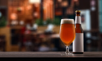 Bottle and glass of beer on counter in pub.