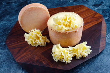 Traditional tete de moine aged mountain cheese of the Alps served on a wooden design board 
