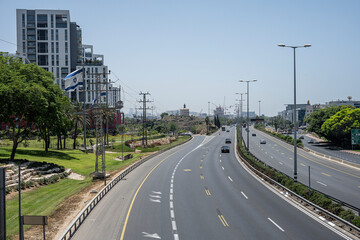 Fototapeta na wymiar Elevated view of Route 2 in Herzliya towards Tel Aviv, Israel Ayalon, in Herzliya, towards Tel Aviv-Yafo, Israel, with buildings and an Israeli flag.