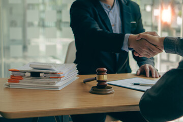 Businessmen and lawyers shake hands to discuss contract documents. Handshake advise after good cooperation Consultation between a male lawyer and a businessman client with a hammer in front.