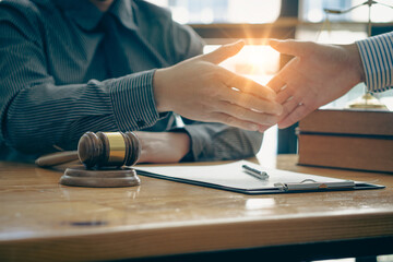 Businessmen and lawyers shake hands to discuss contract documents. Handshake advise after good cooperation Consultation between a male lawyer and a businessman client with a hammer in front.