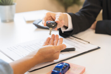 Business car rental company service, Close up hand of agent dealer giving, holding car key to customer renter, new owner after signed rental, purchase contract in document, vehicle sales agreement.