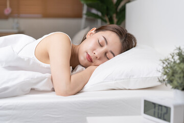 Obraz na płótnie Canvas Sweet dreams, attractive smile pretty asian young woman, girl sleeping in comfortable bed lying on soft pillow resting, keeping eyes closed while with covered blanket in cozy white bed in the morning.