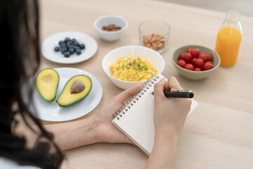 Diet, Dieting hand of asian young woman, girl write diet plan nutrition on table is different food ingredients in the green. Nutritionist of healthy, nutrition of weight loss, health care people.