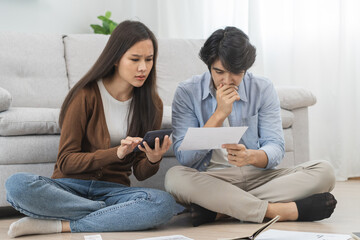 Stressed financial owe asian young couple love sitting suffer, stressed and confused by calculate expense from invoice or bill, no money to pay, mortgage or loan. Debt, bankrupt or bankruptcy people.