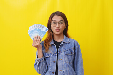 Asian college student standing while holding an Indonesian money. Allowance or scholarship concept