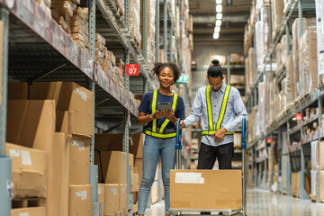 frican American female employee in a warehouse with an Asian male employee  walking and talking together in wholesale shop.Teamwork concept.