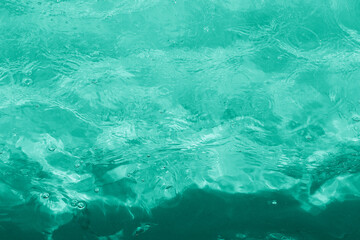 Rippled pattern of clean water in a green swimming pool. Green water texture