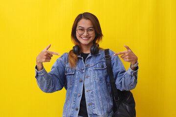 Friendly asian college student standing while presenting something, Isolated on yellow background