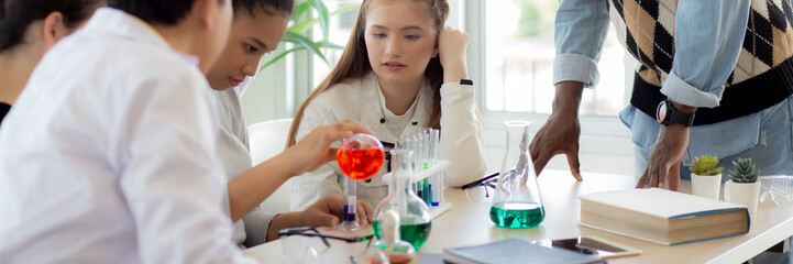 Young teacher teaching group student about science and test chemical for liquid in the lab of school, children studying and learning experiment science in the laboratory, education concept.