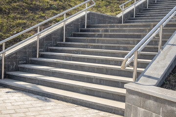 Fototapeta premium Outdoor concrete steps on a modern city staircase with metal railings on a sunny day, outdoors, bottom view