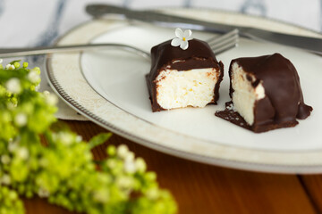 Cut into pieces cottege cheese curd or cheese cake with dark chocolate glaze and white lilac bush