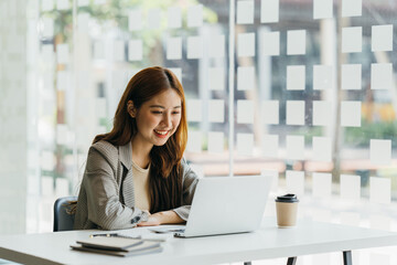 Young beautiful woman using her laptop while sitting in a chair at her working place,  Small business owner people employee freelance online sme marketing e-commerce telemarketing concept.