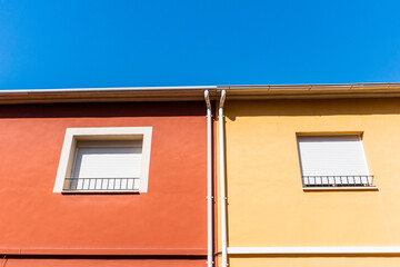 Two house with brown and yellow painted walls, with blue sky in the background. 