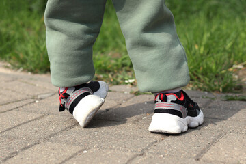 Fototapeta na wymiar Baby's feet in sneakers, sports in a small age. Close-up of a little man's legs