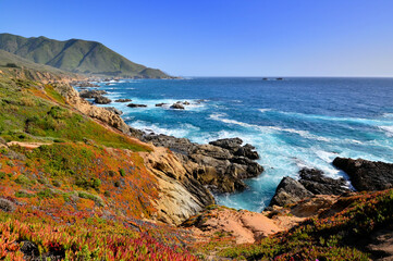 View of the rocky shoreline near Big Sur along the California coast, USA. Late day sun and blue...
