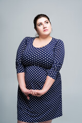 Plus size fashion model in blue polka dot dress, fat woman on gray background, body positive concept - obrazy, fototapety, plakaty